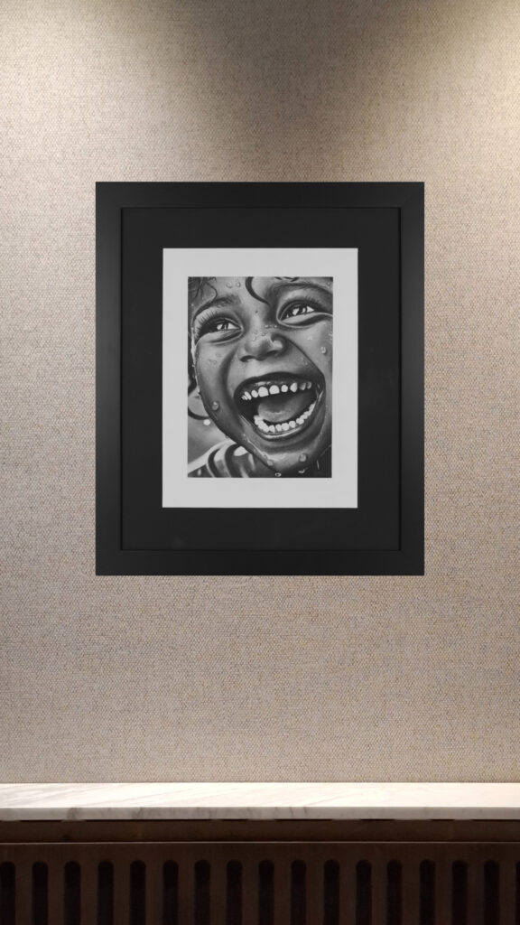 Hyperrealistic charcoal portrait of laughing child, part of Janis Baer’s portrait series