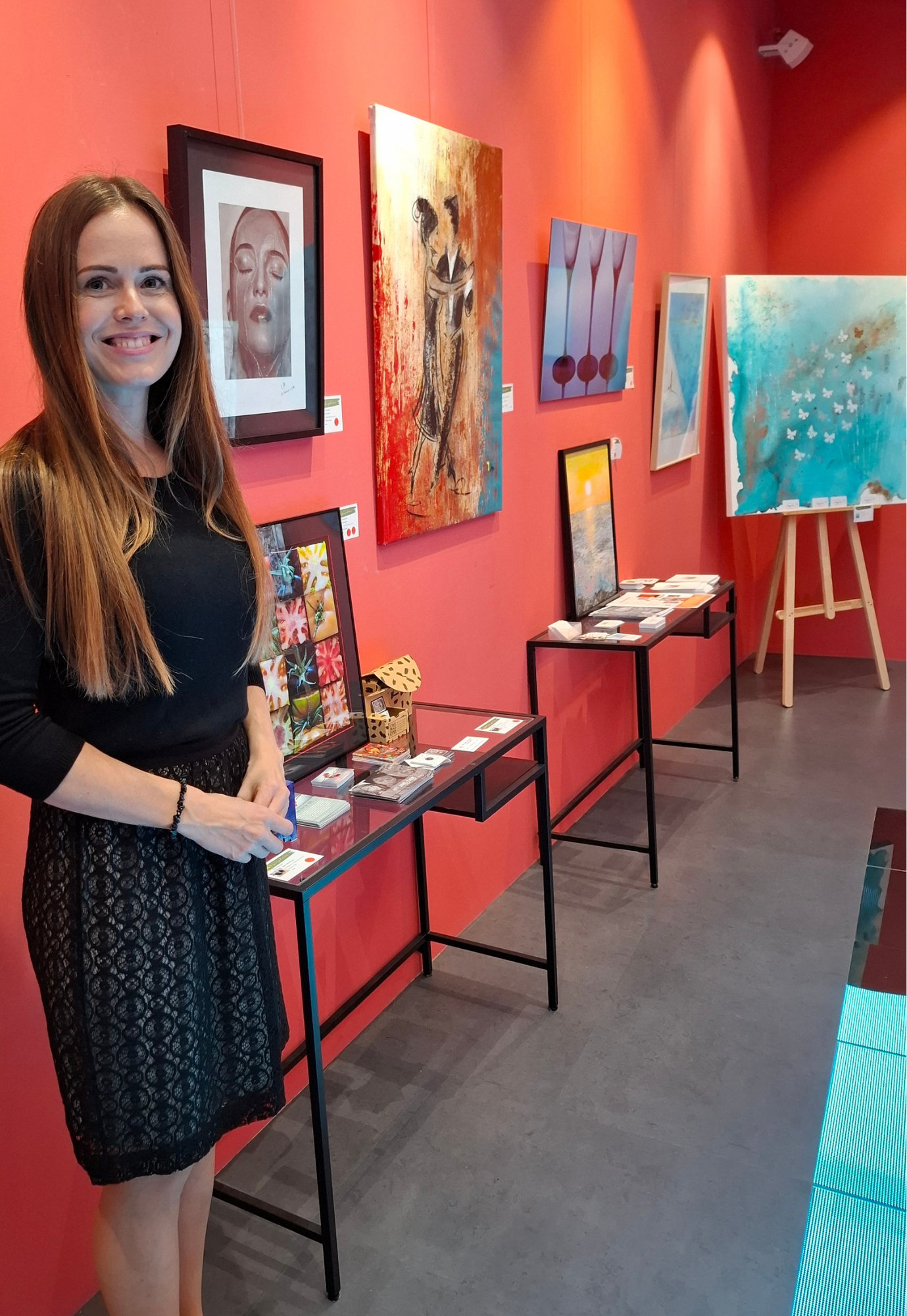 Contemporary artist Janis Bär standing beside her exhibition display during the charity exhibition ART for a Good Reason at Gallery Hotel Artmadams in Palma, Mallorca.